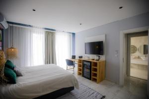 马普托Cowork Lab Suites的一间卧室配有一张床、一张书桌和一台电视