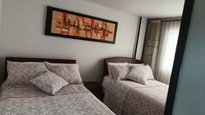 波哥大ApartaHotel Modelia con Parqueadero的卧室配有两张床,墙上挂着一幅画
