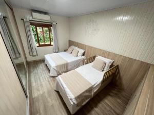格拉玛多Casa mais Central de Gramado的客房设有两张床和窗户。
