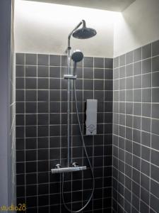 派尔努Studio28 Boutique Rooms的浴室内设有黑色瓷砖淋浴和淋浴头。