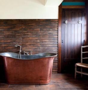 莱斯卡珀利斯博尔波Chambres d'Hôtes Manoir de Beaumarchais的浴室设有铜质浴缸,浴室设有木墙