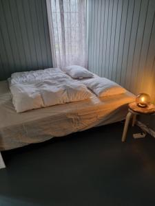 弗勒Stor leilighet med 4 senger sentralt i Førde的卧室内的一张未铺好的床,配有边桌
