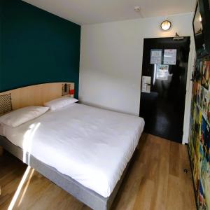 利勒达博里昂东里岛普瑞米尔经典酒店的一间卧室配有一张白色的床和绿色的墙壁
