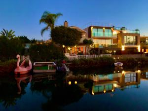 洛杉矶Chic Venice Beach Bungalow Steps from the Canals & Beach的夜间在水中划船的房子