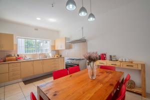 开普敦The Avenue House的厨房配有木桌和红色椅子