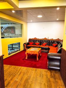 波托西HOSTAL SAN MARCOS POTOSÍ的客厅配有沙发和一张桌子,铺在红色地毯上