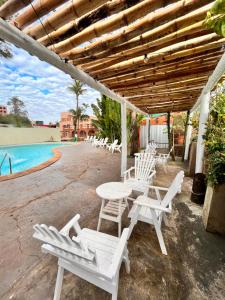 伊瓜苏港ARASARÍ Hotel Iguazú的一个带白色椅子和桌子的庭院和一个游泳池
