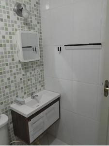 瓜拉派瑞Na frente da Praia do Morro, com Wi-Fi, elevador e TV smart的白色的浴室设有水槽和卫生间。