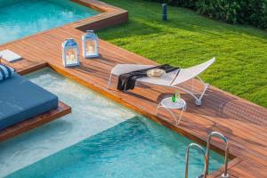 欧拉努波利斯Avaton Luxury Beach Resort - Relais & Chateaux的游泳池设有1个带桌椅的甲板
