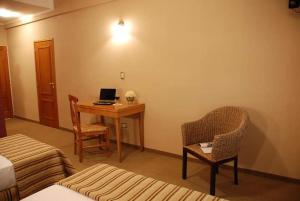 CharataCATANGE HOTEL的酒店客房配有带笔记本电脑和椅子的书桌