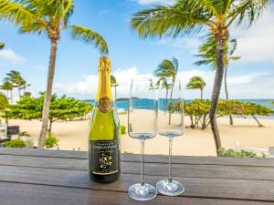 圣马丁岛Studio CASA SUN的海滩附近的桌子上放着一瓶香槟和两杯酒