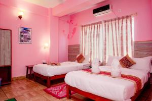 博卡拉Hotel Peace Stupa的配有粉红色墙壁的客房内的两张床