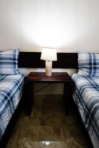 San QuintínHOTEL & RV PARK ROSA EVELYN的一张桌子和灯,放在两张床之间