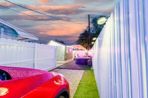 迈阿密花园Smart Tiny House Garden的停在白色围栏旁边的红色汽车