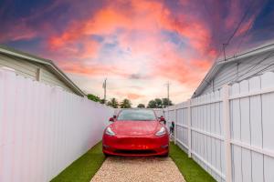 迈阿密花园Smart Tiny House Garden的停在白色围栏旁边的红色汽车