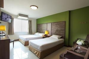 曼谷Rambuttri Village Plaza - SHA Extra Plus的一间酒店客房,设有两张床和绿色的墙壁