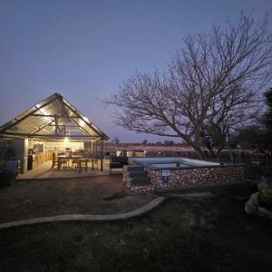 楚梅布Tamboti Farm Accommodation的庭院中带桌子和游泳池的凉亭