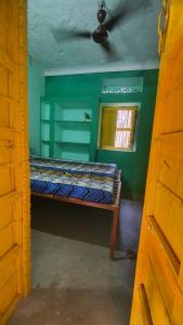 布什格尔ANAND HOSTEL的绿色客房的一张床位,设有窗户