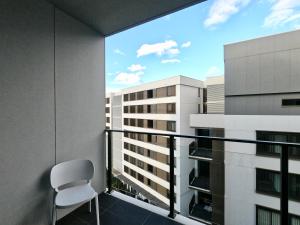 悉尼Spacious1 BR@waterfront Olympic Park_free carpark的享有大楼景致的阳台上的椅子