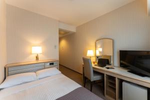 金泽HOTEL MYSTAYS Kanazawa Katamachi的酒店客房配有一张床和一张书桌及一台电视