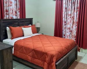 Crocus HillTropix Getaway - rental car available的一间卧室配有一张带橙色棉被和红色窗帘的床