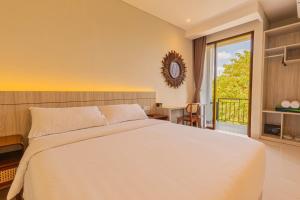 金巴兰The Baliem Hotel的一间带一张白色大床的卧室和一个阳台