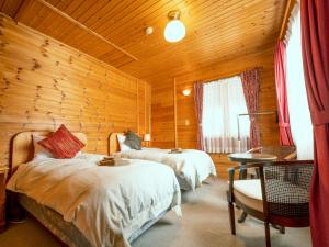 饭山市Madarao Vacance Village的一间卧室设有两张床和木墙