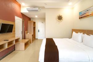 特鲁克巴库Agro Hotel Bintan的一间带大床和电视的卧室