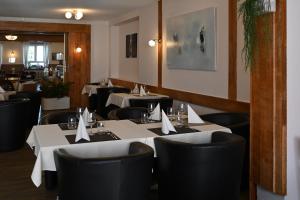 赛尼厄莱吉耶Hôtel de la Gare的一间设有白色桌子和黑色椅子的餐厅