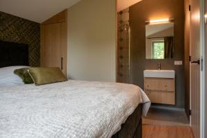 瓦门赫伊曾Parc La Dune Dutch Lodge的一间卧室设有一张大床和一个水槽