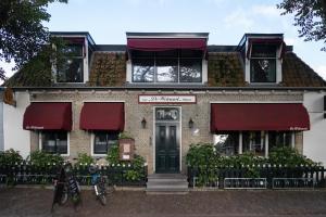 霍勒姆De Welvaart - Logement的砖房,上面有红色遮阳篷