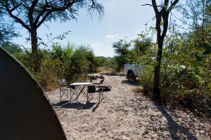 MirapeneSemowi Lodge and Campsites的一张桌子和椅子坐在沙子里,旁边一辆面包车