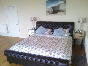 佩恩顿Yew Tree House的一间卧室配有一张大床和黑色皮革床头板