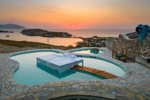 Tzamaria阿加利亚豪华套房别墅的日落时分带桌子和大海的游泳池