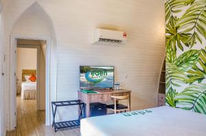 高龙撒冷岛Eden Beach Resort by EHM的一间卧室配有一张桌子和一张带电视的床。