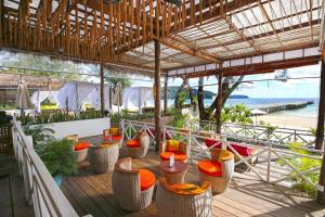 高龙撒冷岛Eden Beach Resort by EHM的海滩甲板上的餐厅,配有桌椅