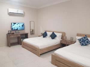 Abyār ‘Alīمورايا Murraya的一间卧室设有两张床,墙上配有电视。