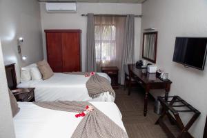 白河Hotel 247 @ White River的酒店客房设有两张床、一张桌子和一台电视。