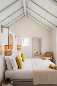 孔波尔塔Independente Comporta的白色卧室配有一张带黄色枕头的大床