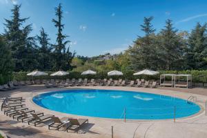 罗马NH罗马卡尔佩尼亚别墅酒店的一个带椅子和遮阳伞的大型游泳池