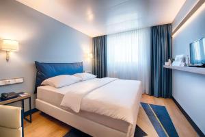 开姆尼茨Congress Hotel Chemnitz的一间卧室设有一张大床和一个窗户。