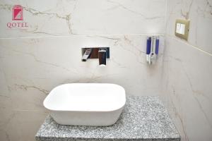 新德里Qotel Hotel Ashok Vihar Couple Friendly的浴室设有位于柜台上的白色卫生间