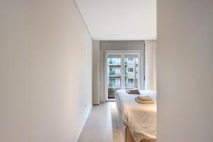 波瓦-迪瓦尔津Póvoa 3 Suites的一间卧室设有一张床和一个窗口