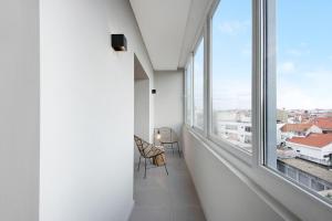 波瓦-迪瓦尔津Póvoa 3 Suites的一间空房间,设有大窗户和椅子