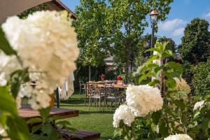 福萨诺La Tenuta di Santo Stefano Agri Resort & Spa的花园内种有白色花卉,配有桌椅