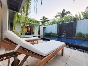 金巴兰Bali - Jimbaran Bay 2 Bedroom Villa的一个带椅子的庭院和一个游泳池
