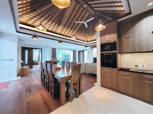 金巴兰Bali - Jimbaran Bay 2 Bedroom Villa的厨房以及带木桌和椅子的用餐室。