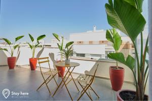 拉巴特Stayhere Rabat - Agdal 4 - Hotel的阳台种植了盆栽植物,配有桌椅