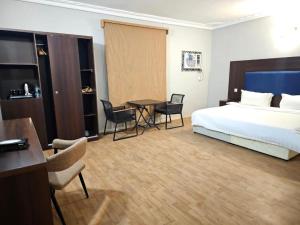 延布Safa PARK HOTEL YANBU فندق صفا بارك ينبع的酒店客房带一张床、一张桌子和椅子