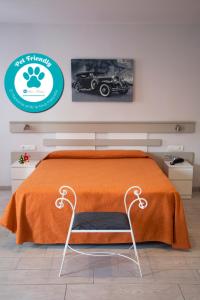 卡里拉Apartamentos Comfort Calella的一张带橙色毯子的床和一把椅子